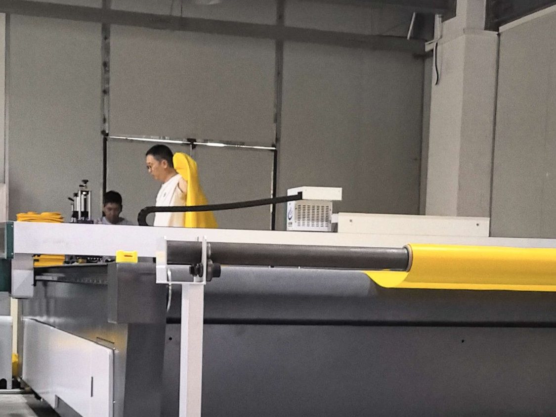Operators at a CNC cutter with yellow PVC-coated polyester in the Taizhou factory